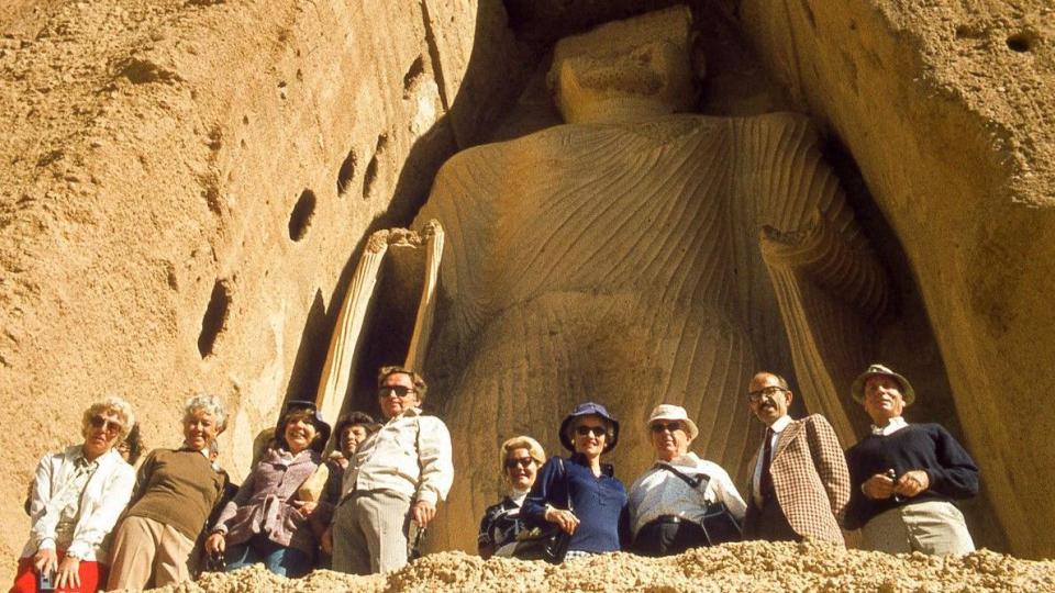 View of Western tourists posing before the massive height of the smaller giant Buddha, known as Shamama, in Bamiyan, Hazarajat region, central Afghanistan, November, 1975.