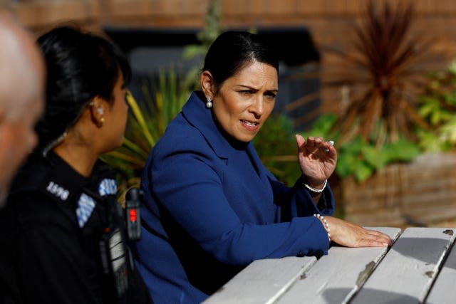 Former Home Secretary Priti Patel speaking to a uniformed police officer.