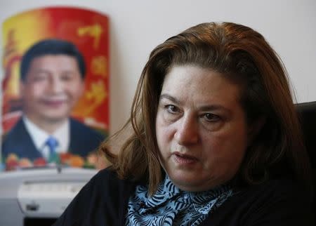 Ursula Gauthier, a French journalist of the weekly l'Obs news magazine, reacts in her room as a poster of China's President Xi Jinping is seen in the background during an interview with Reuters in Beijing, China December 29, 2015.REUTERS/Kim Kyung-Hoon