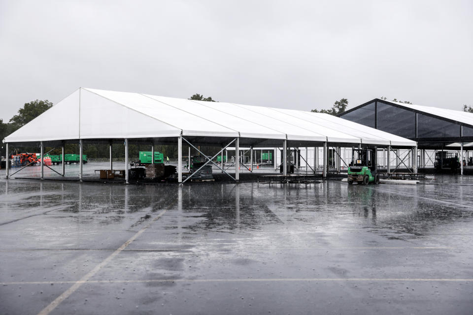 Workers disassemble hangar-sized tents, Tuesday, Oct. 4, 2022, in the parking lot of Orchard Beach in the Bronx borough of New York. Giant tents for temporarily housing migrants arriving in New York City are being moved to an island off Manhattan from a remote corner of the Bronx, after storms raised concerns over flooding at the original site. (AP Photo/Julia Nikhinson)