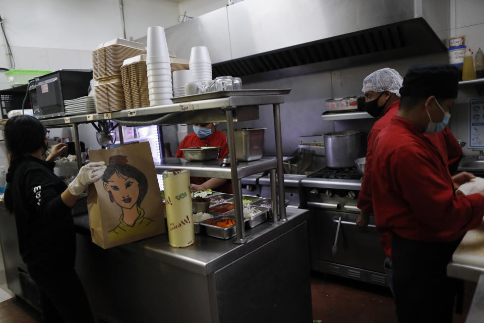 Staff prepare a takeout order at Maviri seafood restaurant, where workers say the company has helped them by continuing to provide full employment, despite the big drop in sales amid the restrictions of the COVID-19 pandemic, in the Condesa neighborhood of Mexico City, Sunday, Jan. 10, 2021. Worried about their ability to survive, many restaurants in the capital and adjacent Mexico State are banning together in a campaign dubbed "Abrir o Morir," Spanish for "Open or Die," and plan to open their doors to diners again on Monday in defiance of ordinances limiting restaurants to takeout service while the Mexico Valley remains under red alert with hospitals nearing full capacity. (AP Photo/Rebecca Blackwell)