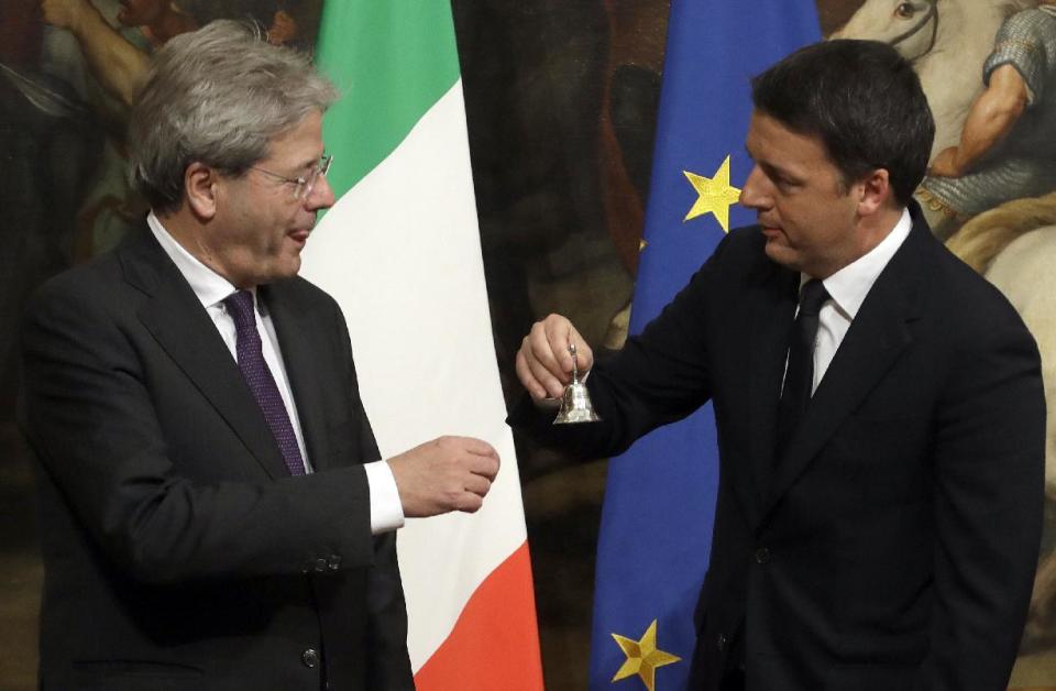 Italian outgoing Premier Matteo Renzi, right, hands over the cabinet minister bell to new Premier Paolo Gentiloni during the handover ceremony at Chigi Palace Premier's office, in Rome, Monday, Dec. 12, 2016. Paolo Gentiloni, a Democrat serving as foreign minister, formed Italy’s new government Monday, keeping several key ministers from the coalition of Matteo Renzi, who resigned last week. (AP Photo/Gregorio Borgia)