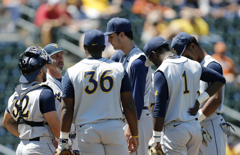 FILE - West Virginia head coach Randy Mazey, second from left, talks to starting pitcher Jackson Wolf, center, during an NCAA college baseball game Saturday, April 27, 2019, in Austin, Texas. West Virginia doesn’t have a softball team. Iowa State has no baseball team. So a friendship was formed between the Big 12 schools' existing squads on the diamond as well as among their fans. "It’s kind of taken a life of its own, it appears,” West Virginia coach Randy Mazey said.(AP Photo/Chris Covatta, File)