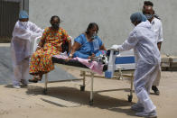 Health worker carry patients to shift them from a dedicated COVID-19 hospital to another hospital to vacate the bed for new patients, at Civil hospital in Ahmedabad, India, Tuesday, April 13, 2021. India has been overwhelmed by hundreds of thousands of new coronavirus cases daily, bringing pain, fear and agony to many lives as lockdowns have been placed in Delhi and other cities around the country. (AP Photo/Ajit Solanki)