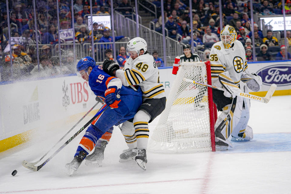 New York Islanders right wing Julien Gauthier (16) is checked by Boston Bruins defenseman Matt Grzelcyk (48) during the second period of an NHL hockey game in Elmont, N.Y., Friday, Dec. 15, 2023. (AP Photo/Peter K. Afriyie)
