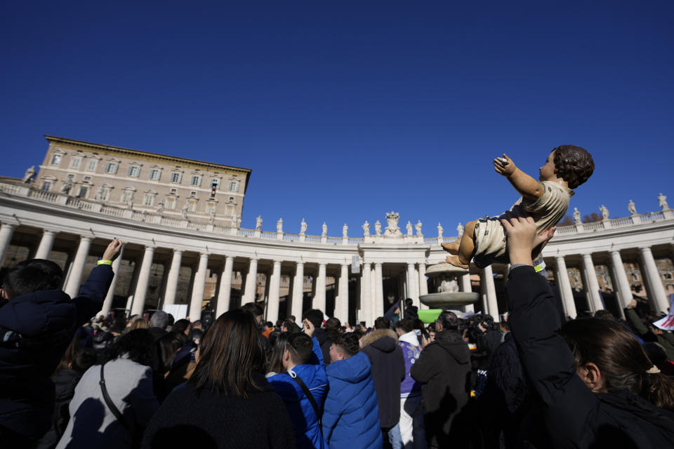 A child holds up a statue of baby Jesus as Pope Francis blesses them during the Angelus noon prayer he celebrated from the window of his studio overlooking St.Peter's Square, at the Vatican, Sunday, Dec. 17, 2023. (AP Photo/Alessandra Tarantino)