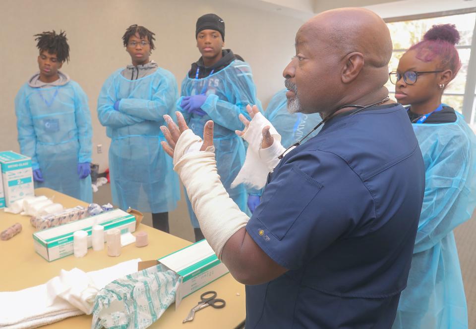 Dr. Gregory Hill, an orthopedic surgeon with Unity Health Network and chairman of the department of surgery at Western Reserve Hospital, demonstrates how to cast a broken bone to Buchtel high school students during the Black Men in White Coats Summit at the University of Akron.