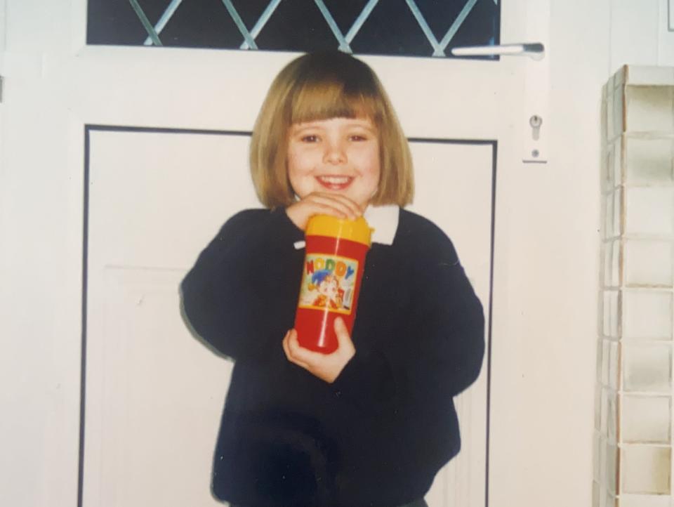 Chloe-Louise Bond poses in her school uniform and drinks from a colorful water bottle around the age of 7 when she was formally diagnosed with ADHD.