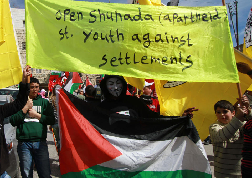 Palestinians hold a banner in the center of the West Bank city of Hebron, Friday, Feb. 21, 2014, during a demonstration against the closure of the main downtown street. Shuhada street was shut after a 1994 mosque massacre when a settler shot and killed 29 Muslim worshippers. The military closed it citing security reasons. (AP Photo/Nasser Shiyoukhi)