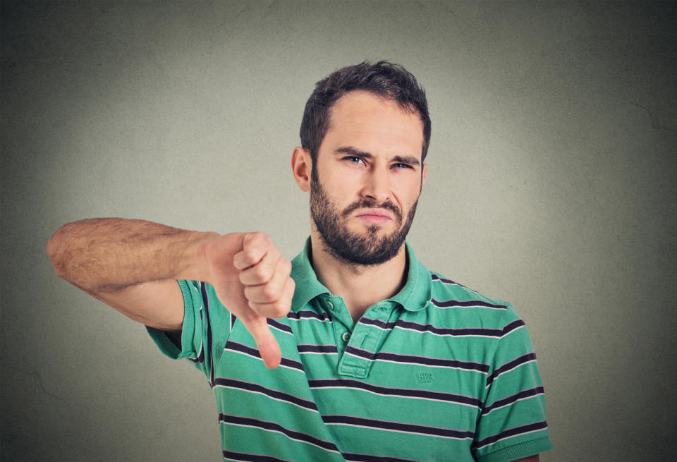 Man with frown holding his thumb down