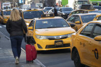 A traveler waits for a taxi, Wednesday, Jan. 29, 2020, in New York. A task force studying New York City's struggling taxi industry called Friday for “mission-driven” investors to help bail out drivers who incurred massive debt once the value of the medallion that allows a person to operate a yellow cab plummeted in the age of Uber and Lyft. (AP Photo/Mark Lennihan)