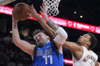 Dallas Mavericks guard Luka Doncic (77) and San Antonio Spurs center Victor Wembanyama (1) reach for a rebound during the second half of an NBA basketball game in San Antonio, Tuesday, March 19, 2024. (AP Photo/Eric Gay)