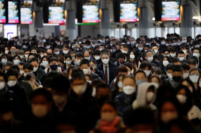 Commuters wearing protective face masks amid the COVID-19 pandemic make their way at a train station in Tokyo