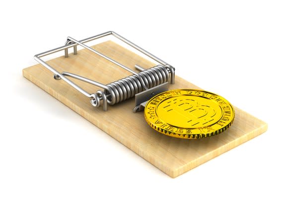 A physical gold bitcoin used as bait in a mouse trap.