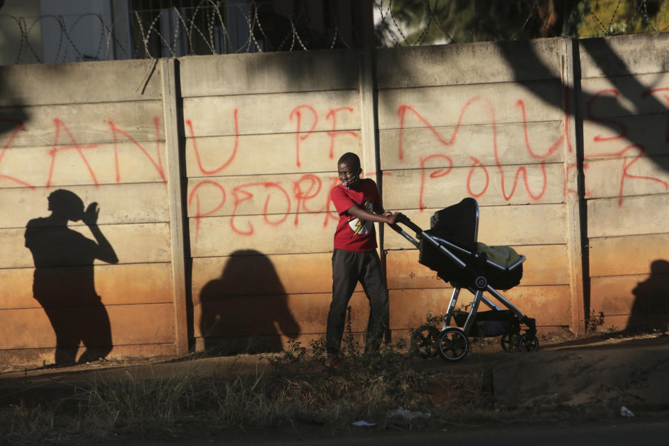 A young boy pushes a pram past a wall with graffiti advocating for People Power ,on the streets of Harare in this Tuesday, July, 7, 2020 photo. Unable to protest on the streets, some in Zimbabwe are calling themselves "keyboard warriors" as they take to graffiti and social media to pressure a government that promised reform but is now accused of gross human rights abuses.(AP Photo/Tsvangirayi Mukwazhi)