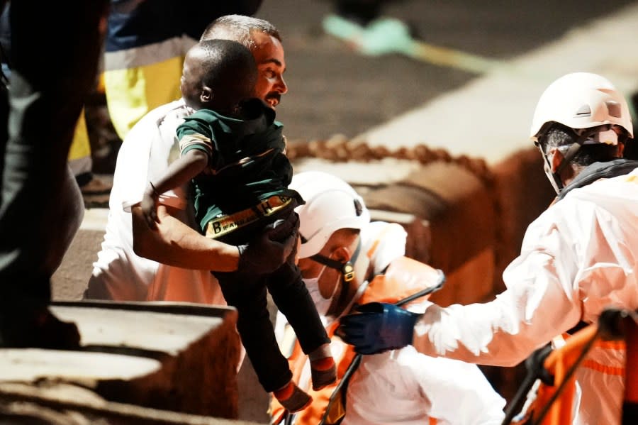 A boy is held by a rescue worker at the port in La Restinga, on the Canary island of El Hierro on Saturday, Nov. 4, 2023. More than 32,000 migrants have landed in Spain’s Canary Islands this year setting a new record for the number of irregular arrivals to the archipelago. Most migrants taking the dangerous Atlantic boat journey are leaving from Senegal. (Humberto Bilbao/Europa Press via AP) **SPAIN OUT**