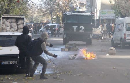 Kurdish demonstrators throw stones at a police vehicle during a protest against the curfew in Sur district, in the southeastern city of Diyarbakir, Turkey, December 22, 2015. REUTERS/Sertac Kayar