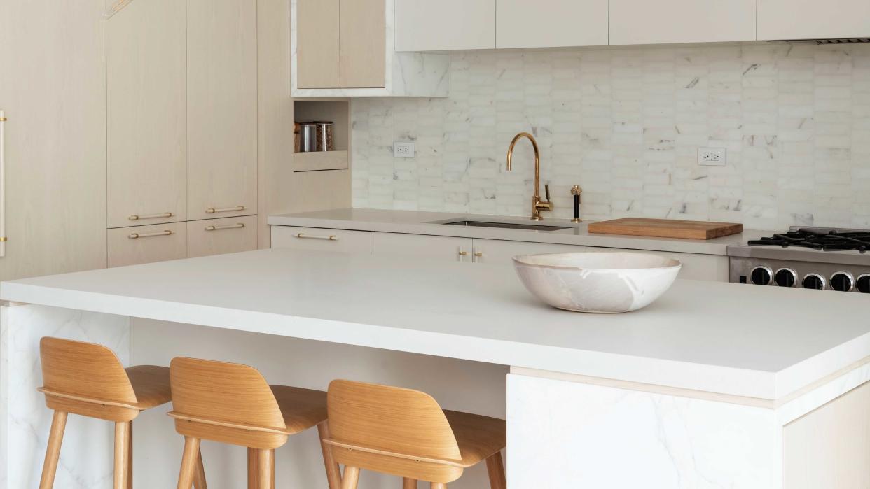  A white kitchen with a quartz countertop. 