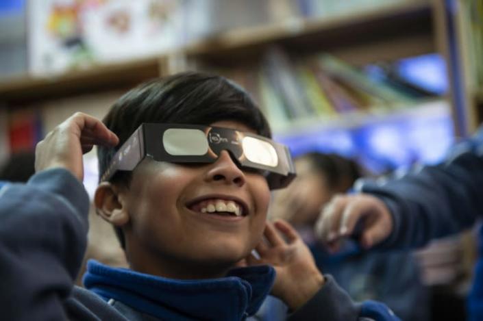 A schoolboy tries on special sunglasses at the Pedro Pablo Munoz school in La Higuera, Coquimbo Region, Chile, on the eve of a solar eclipse (AFP Photo/Martin BERNETTI)
