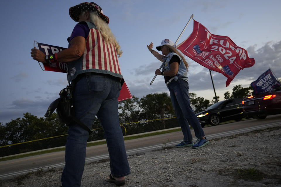 Trump supporters "Maga" Mary Kelley, right, of Lake Worth, and Kathy Clark of Lantana carry flags as they protest following the news that former President Donald Trump has been indicted by a Manhattan grand jury, Thursday, March 30, 2023, near his Mar-a-Lago estate in Palm Beach, Fla. Trump has been indicted by a Manhattan grand jury, prosecutors and defense lawyers said Thursday, making him the first former U.S. president to face a criminal charge and jolting his bid to retake the White House next year. (AP Photo/Rebecca Blackwell)