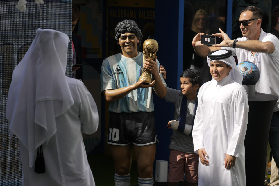 Children pose for a picture with a statue of the late soccer star Diego Maradona during a commemoration in his honor in Doha, in Friday, Nov. 25, 2022. (AP Photo/Jorge Saenz)