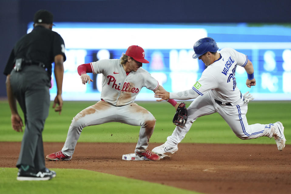 Philadelphia Phillies second baseman Bryson Stott, center, tags out Toronto Blue Jays' Daulton Varsho (25) trying to steal second base during seventh inning of a baseball game in Toronto on Tuesday, Aug. 15, 2023. (Nathan Denette/The Canadian Press via AP)