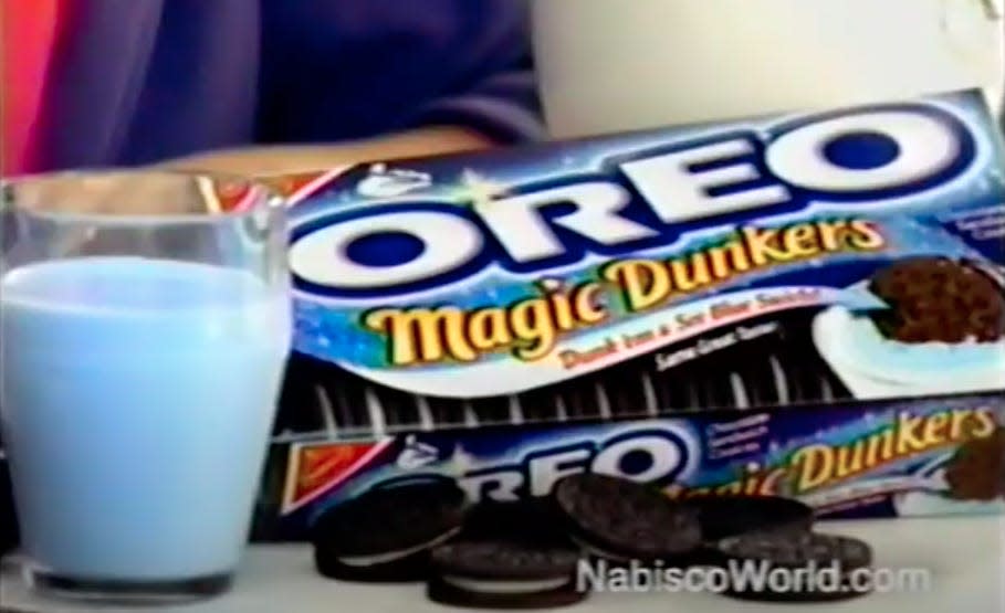 A package of Oreo Magic Dunkers sits next to a glass of blue-colored milk and several cookies, as seen in a television ad for the product