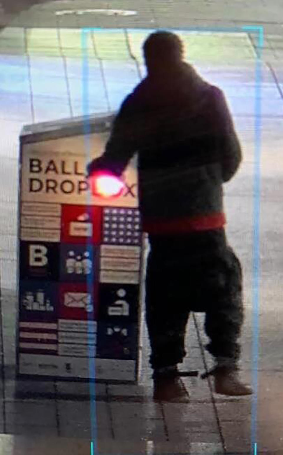 This surveillance image provided by the Boston Police Department shows a man approaching a ballot drop box outside the Boston Public Library, early Sunday, Oct. 25, 2020, in downtown Boston. Massachusetts election officials say a fire was set at the ballot drop box holding more than 120 ballots in what appears to have been a “deliberate attack." Boston Police say that an arson investigation is underway and the person shown in this surveillance image is a person of interest. (Courtesy of Boston Police Department via AP)