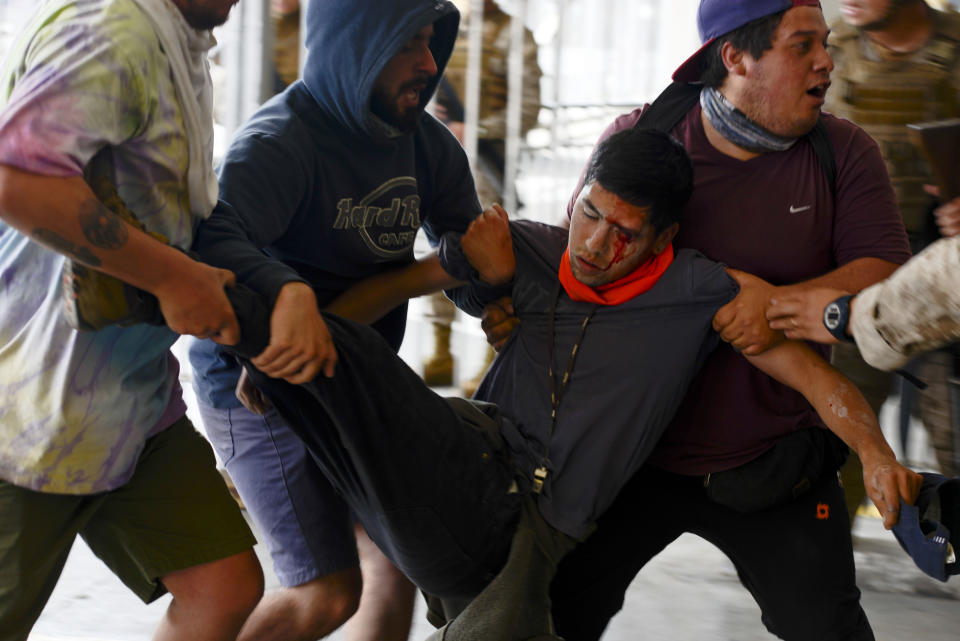 An anti-government protester is carried away after being injured during clashes with police in Valparaiso, Chile, Friday, Oct. 25, 2019. A new round of clashes broke out Friday as demonstrators returned to the streets, dissatisfied with economic concessions announced by the government in a bid to curb a week of deadly violence. (AP Photo/Matias Delacroix)