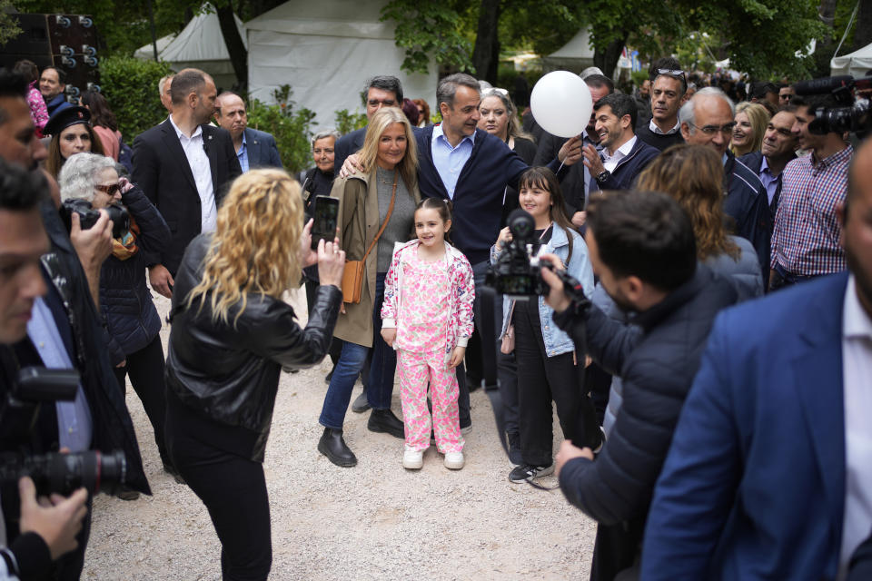 Greece's Prime Minister and New Democracy leader Kyriakos Mitsotakis, center, holds a balloon as he poses with his wife Mareva Grabowski and two girls for a photograph during his election campaign in northern Athens, Greece, Monday, May 1, 2023. (AP Photo/Thanassis Stavrakis)