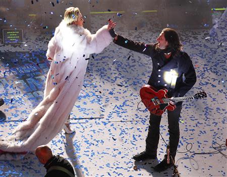 Miley Cyrus (L) congratulates a member of her band after performing for revelers in Times Square during New Year's Eve celebrations in New York December 31, 2013. REUTERS/Gary Hershorn