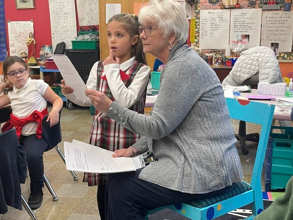 First-grade student Gracelyn Roy with her teacher, Laurie Barrett, asking Peter Petrides questions about being a veteran during a Veterans Day event at St. James School in Danielson.