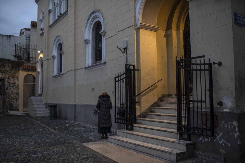 A woman prays outside an Orthodox Church in the Monastiraki district of Athens, on Sunday Dec. 20, 2020. Despite six weeks of lockdown measures, coronavirus deaths and infections remain high, piling pressure on the country's health system.(AP Photo/Petros Giannakouris)