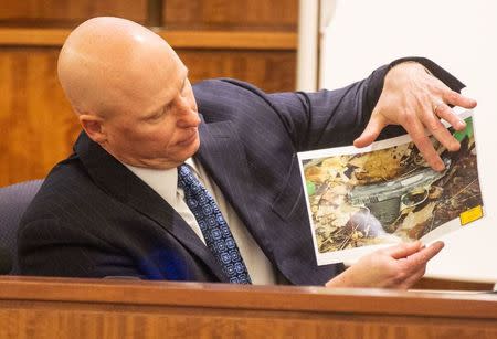 Massachusetts State Trooper Stephen Gallagher holds a picture of a small handgun found in a wooded area near the crime scene during the murder trial of the former New England Patriots player Aaron Hernandez at the Bristol County Superior Court in Fall River, Massachusetts February 13, 2015. REUTERS/Aram Boghosian/Pool
