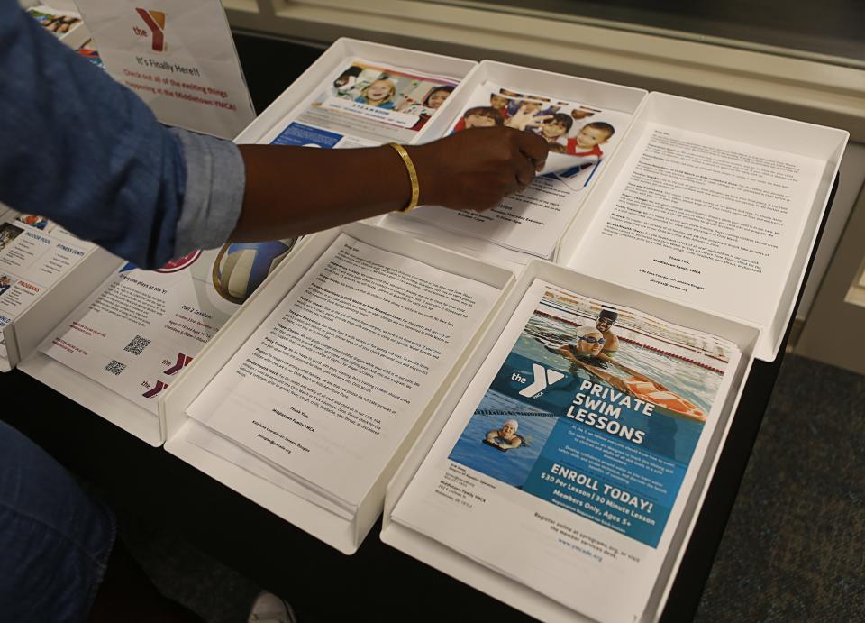 A woman taking a tour of the new Middletown YMCA takes a flyer about child care services provided at the site which opens on September 18, 2023.