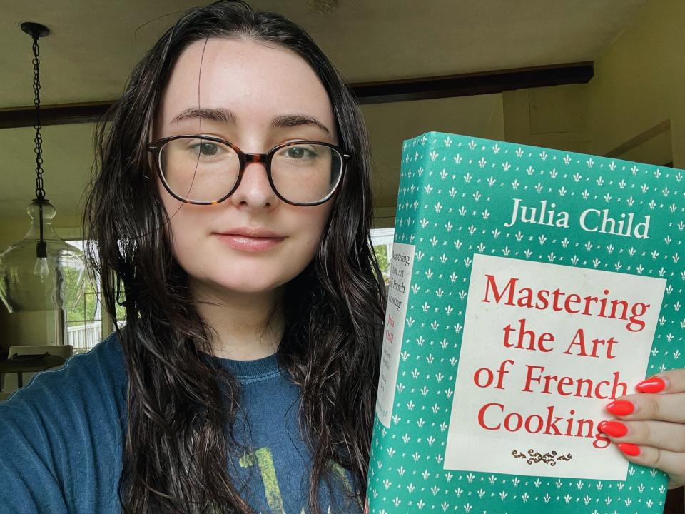 author holding mastering the art of french cooking by julia child