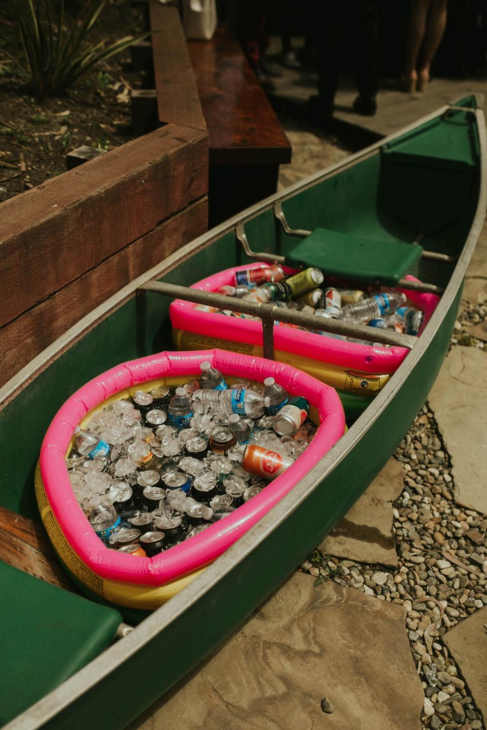 A canoe with two baby pools full of ice and drinks.