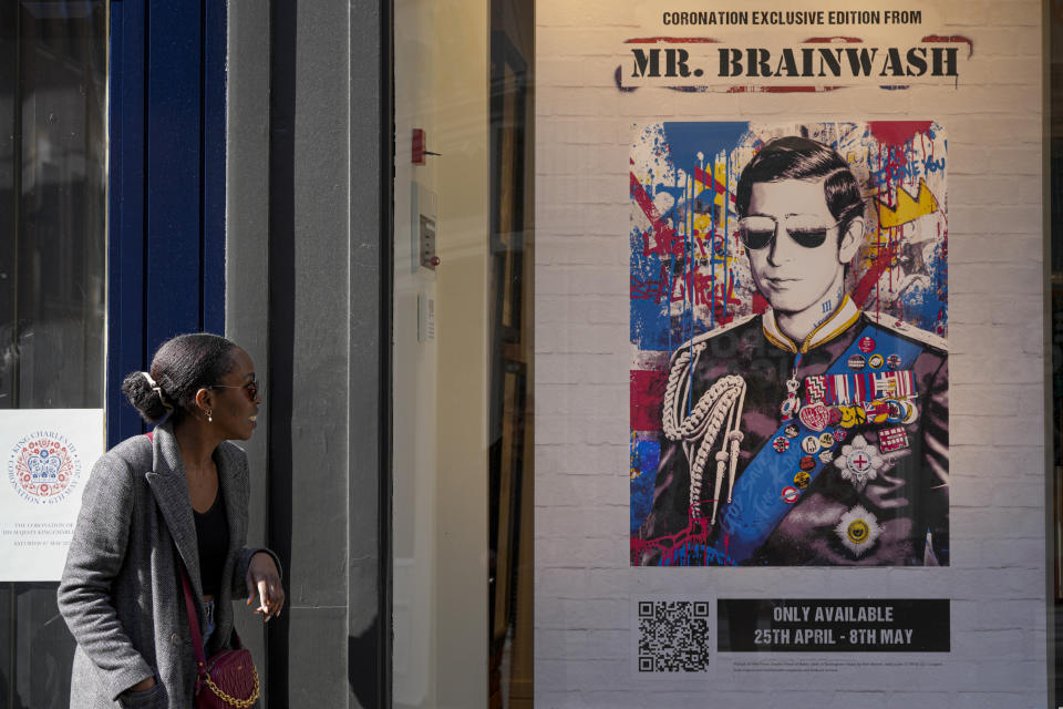 A woman smiles as she looks at a poster with a portrait of King Charles III in Central London, Wednesday, May 3, 2023. The Coronation of King Charles III will take place at Westminster Abbey on May 6. (AP Photo/Andreea Alexandru)