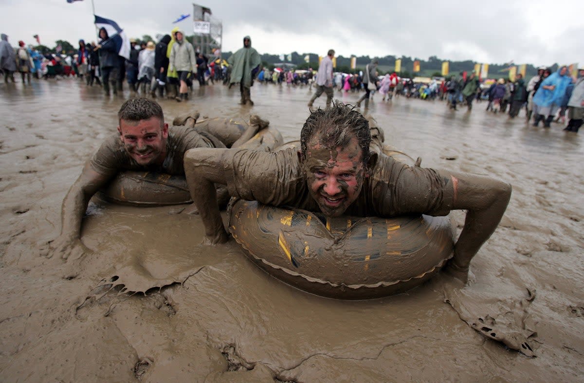 Two festival-goers sliding in the mud in 2007 (Getty Images)