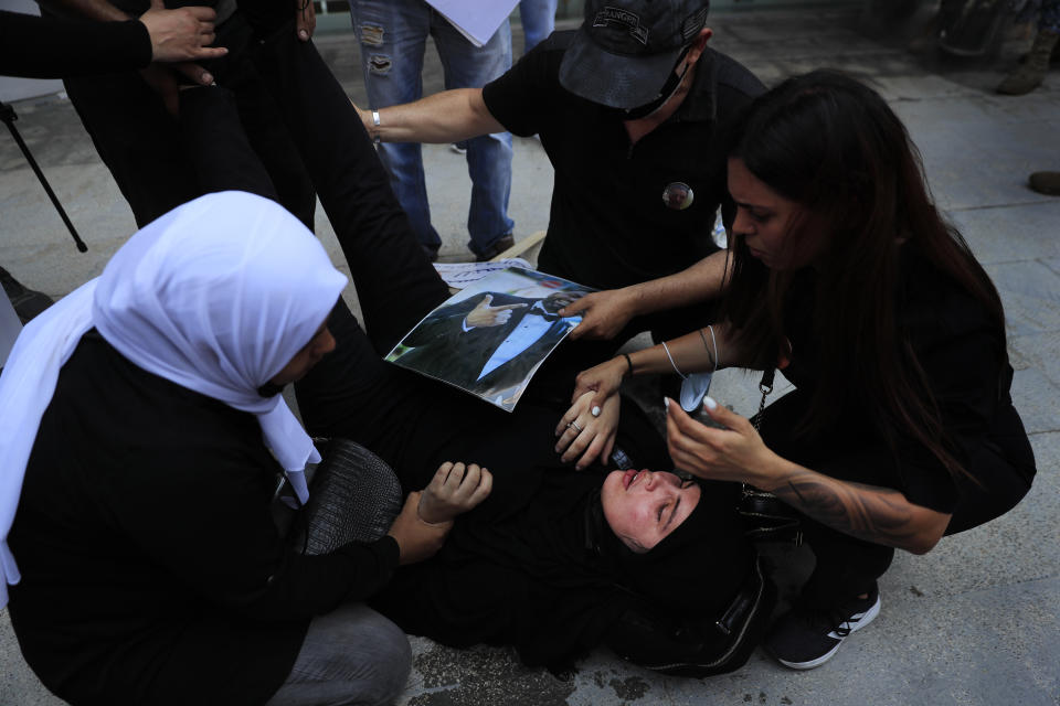 Families of the victims of last year's massive blast at Beirut's seaport, treat a woman who fell down while she was trying with others to reach the tightly-secured residents of parliament speaker Nabih Berri and was pushed back by Lebanese army soldiers, in Beirut, Lebanon, Friday, July 9, 2021. The protest came after last week's decision by the judge to pursue senior politicians and former and current security chiefs in the case, and requested permission for their prosecution. (AP Photo/Hussein Malla)