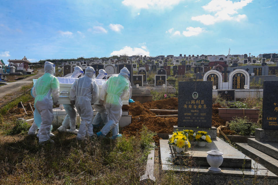 Workers wearing personal protective equipment (PPE) carry a coffin containing the body of a person who died from Covid-19 at the Meru Christian Cemetery in Klang, August 9, 2021. ― Picture by Yusof Mat Isa