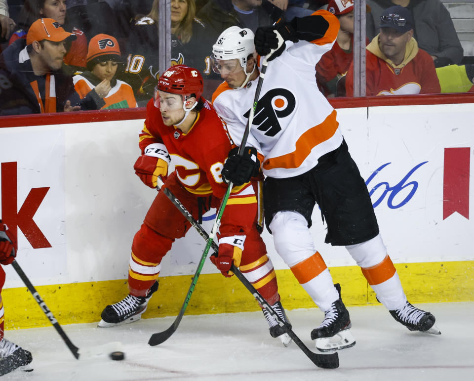 Philadelphia Flyers defenseman Justin Braun, right, checks Calgary Flames forward Andrew Mangiapane during the second period of an NHL hockey game in Calgary, Alberta, Monday, Feb. 20, 2023. (Jeff McIntosh/The Canadian Press via AP)