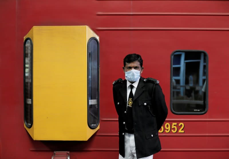 FILE PHOTO: A conductor wears a protective mask as he stands next to a train at Fort railway station, as the number of people who tested positive for coronavirus disease (COVID-19) in the country increased, in Colombo