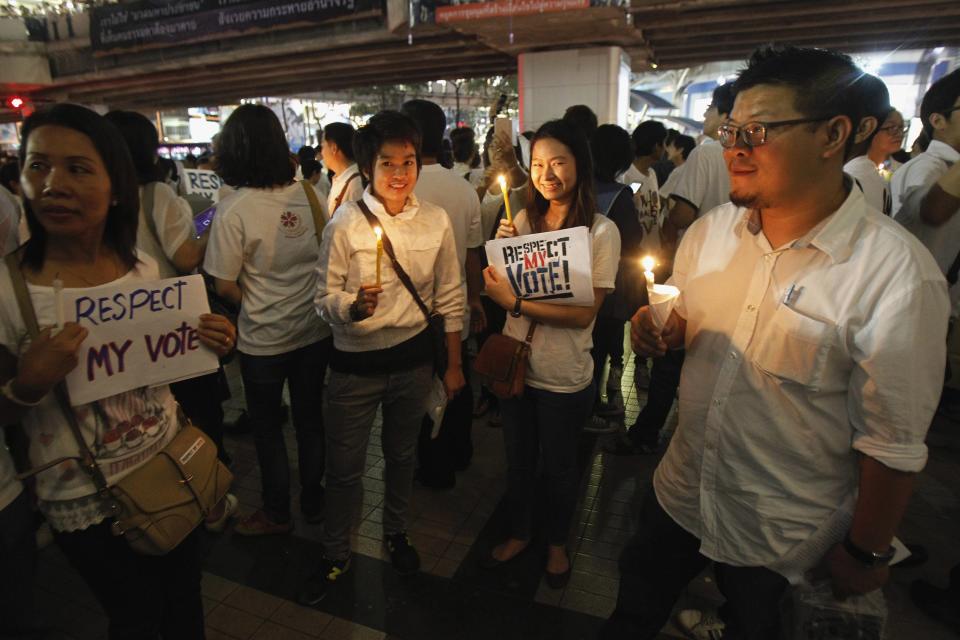 People hold candles and placards during an anti-violence campaign in central Bangkok January 10, 2014. Thailand on Friday played down talk of a military coup ahead of a planned "shutdown" of the capital next week by protesters trying to overthrow Prime Minister Yingluck Shinawatra and said life would go on much as normal. REUTERS/Chaiwat Subprasom (THAILAND - Tags: POLITICS CIVIL UNREST)