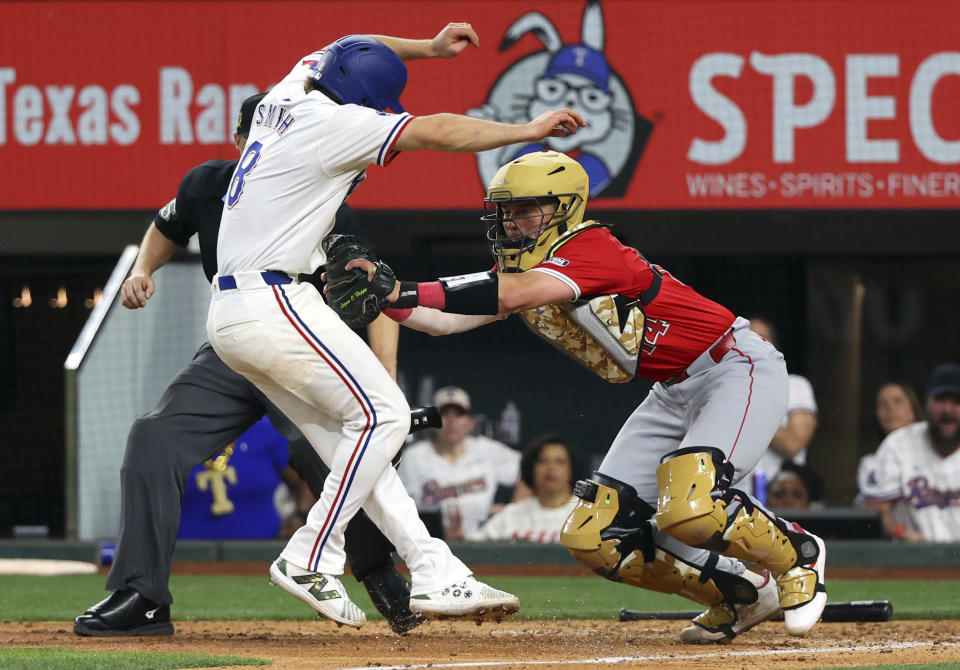 Texas Rangers' Josh Smith (8) is tagged out at the plate by Los Angeles Angels catcher Logan O'Hoppe (14) in the tenth inning of a baseball game Saturday, May 18, 2024, in Arlington, Texas. (AP Photo/Richard W. Rodriguez)