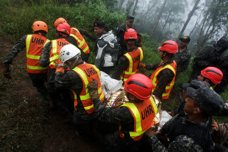 Rescue workers carry a body found in the area where Hilda Hernandez, the sister of Honduran President Juan Orlando Hernandez, and five others died when the helicopter they were traveling in crashed in San Matias, Honduras, December 17, 2017. REUTERS/ Jorge Cabrera