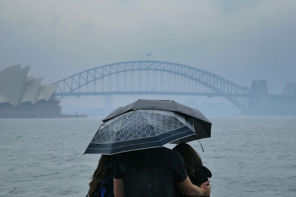 Tourists are seen looking at The Sydney Harbour Bridge in the rain (Getty Images)