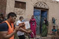 Non-governmental organization Resala Nour Ala Nour workers distribute cartons filled with food to people who have been greatly affected by the coronavirus outbreak, in Cairo, Egypt, Thursday, April 9, 2020. (AP Photo/Nariman El-Mofty)