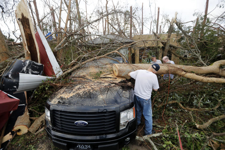 People cut away a tree on a vehicle in Panama City.