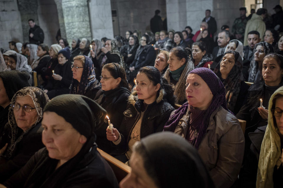 People attend Christmas Eve's Mass in the Assyrian Orthodox church of Mart Shmoni, in Bartella, Iraq, Saturday, December 24, 2016. For the 300 Christians who braved rain and wind to attend the mass in their hometown, the ceremony provided them with as much holiday cheer as grim reminders of the war still raging on around their northern Iraqi town and the distant prospect of moving back home. Displaced when the Islamic State seized their town in 2014, they were bused into the town from Irbil, capital of the self-ruled Kurdish region, where they have lived for more than two years. (AP Photo/Cengiz Yar)